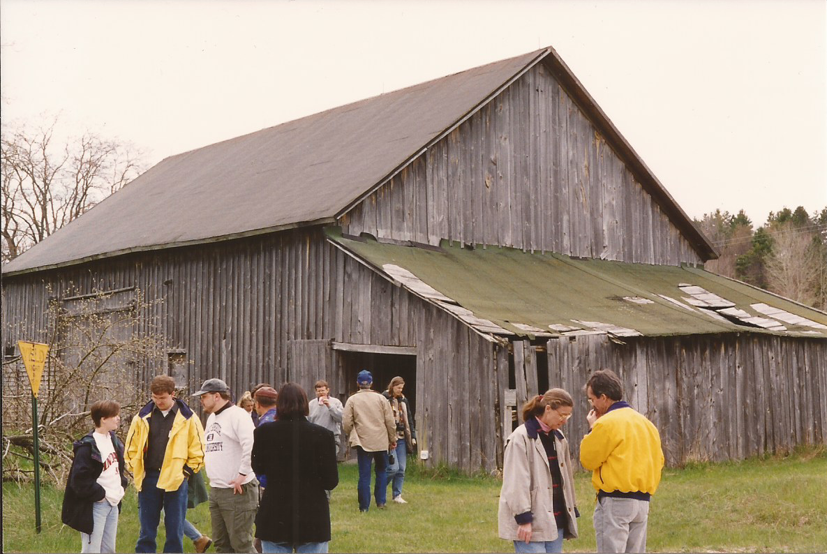 people standing and talking outside a wooden barn